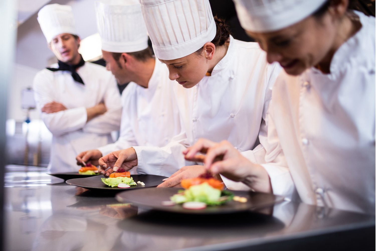 Chefs in a kitchen preparing dishes on plates