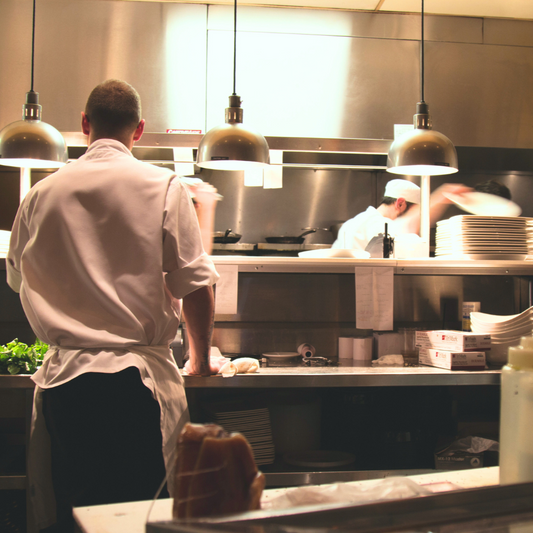 Busy kitchen with chefs at work, illuminated by pendant lights.