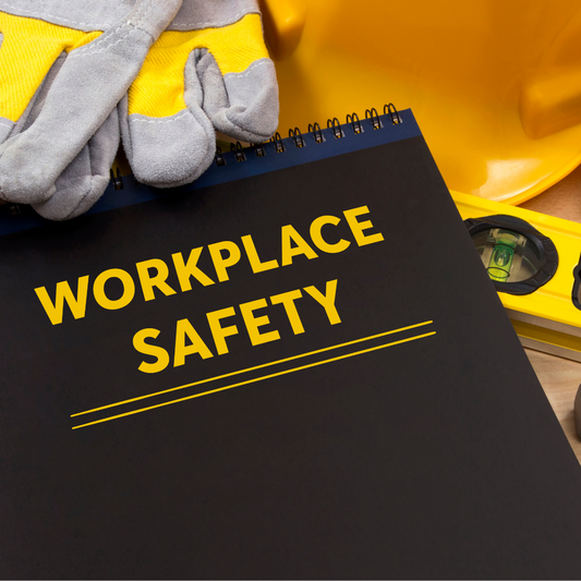 Notebook titled 'Workplace Safety' with safety gear including gloves, helmet, and tools on a wooden surface.