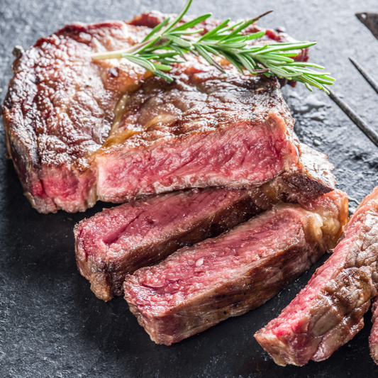 Sliced steak with a knife on a dark surface